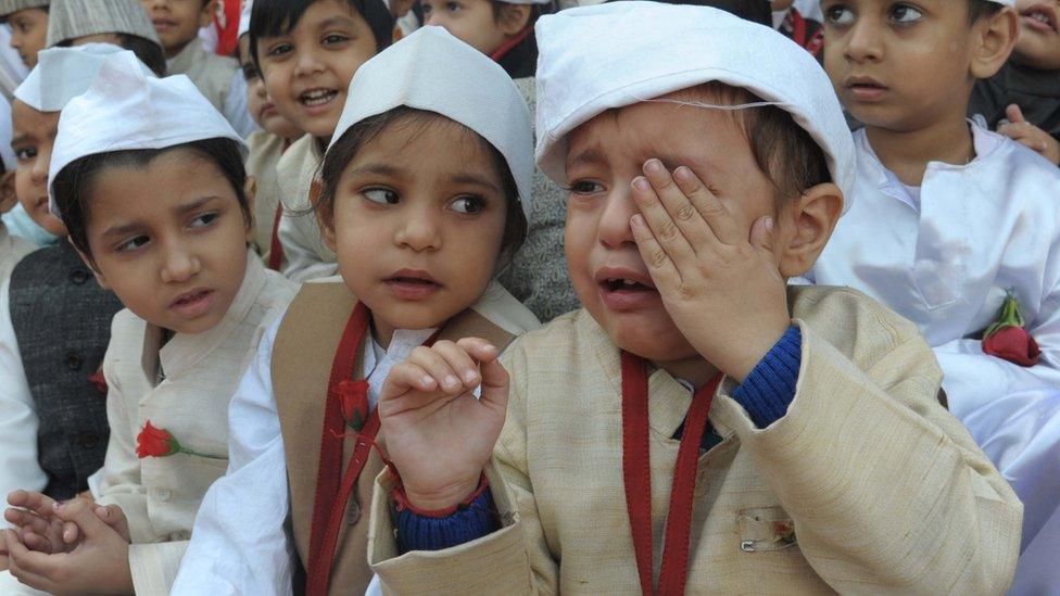 An Indian schoolboy (R) cries and he and schoolmates, dressed up as India's first prime minister Jawaharlal Nehru, pose during a photo event for Children's Day celebrations at a school in Amritsar