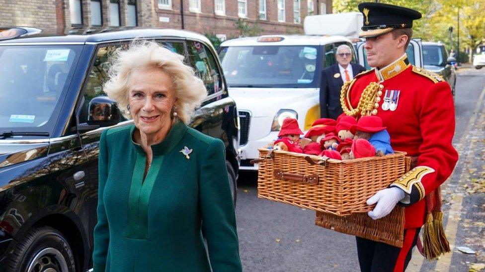 Camilla, her equerry carrying a basket full of Paddington Bears