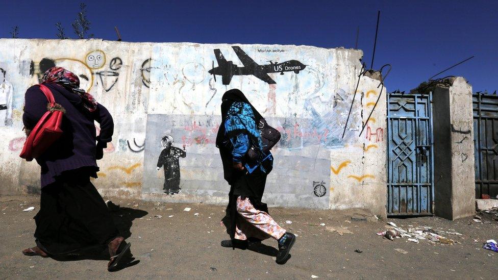 Yemeni women walk past graffiti protesting against US drone strikes on a wall in Sanaa, Yemen (24 December 2016)