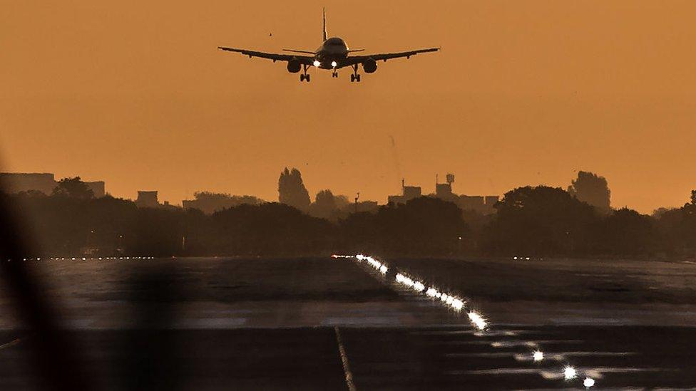 A passenger aircraft prepares to land during sunrise at London Heathrow Airport