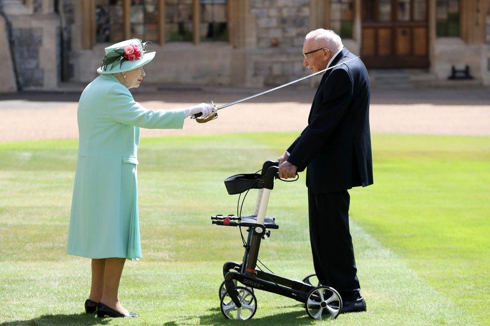 The Queen knights Sir Captain Tom Moore using a sword in the grounds of Windsor Castle