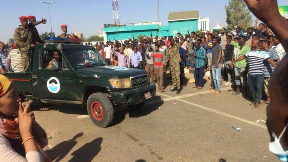 An army vehicle passes protesters near the military HQ on Monday morning