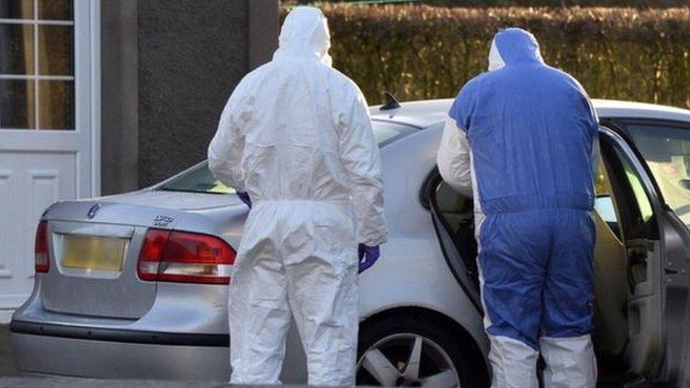 Forensic investigators examining a car at the scene of the murder