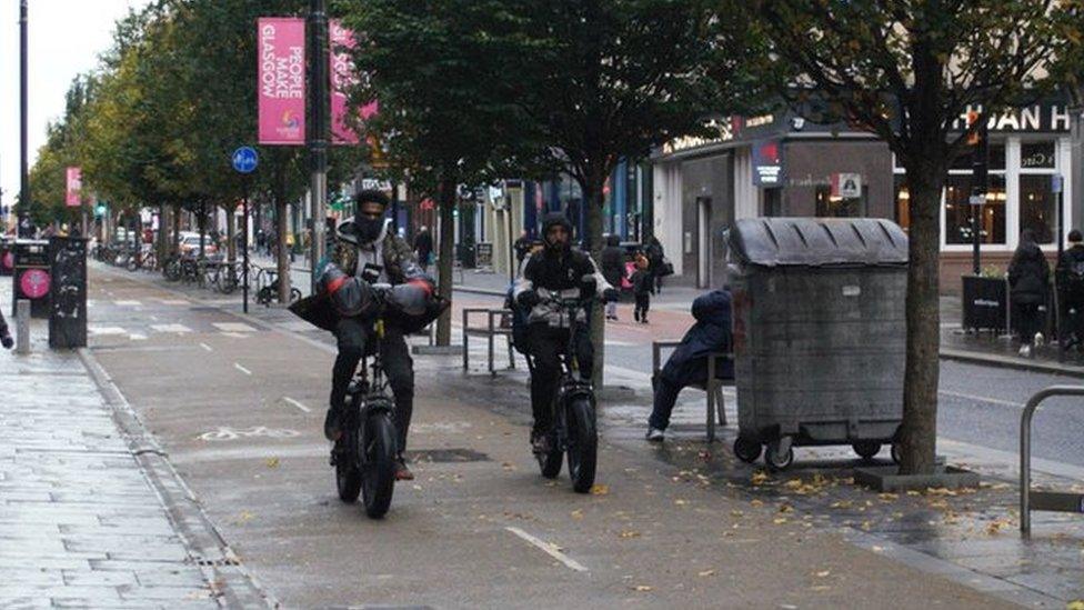 A courier on an e-bike overtaking another e-bike