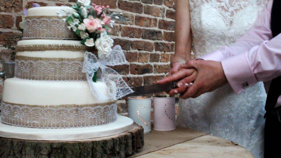 A newly-married couple cut their wedding cake