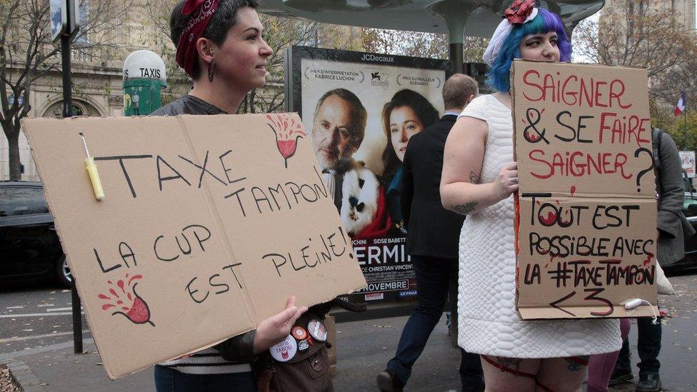 Women hold signs reading 'Tampon tax, the cup is full' during a demonstration in Paris on November calling for reduced taxes on tampons and women's sanitary products.