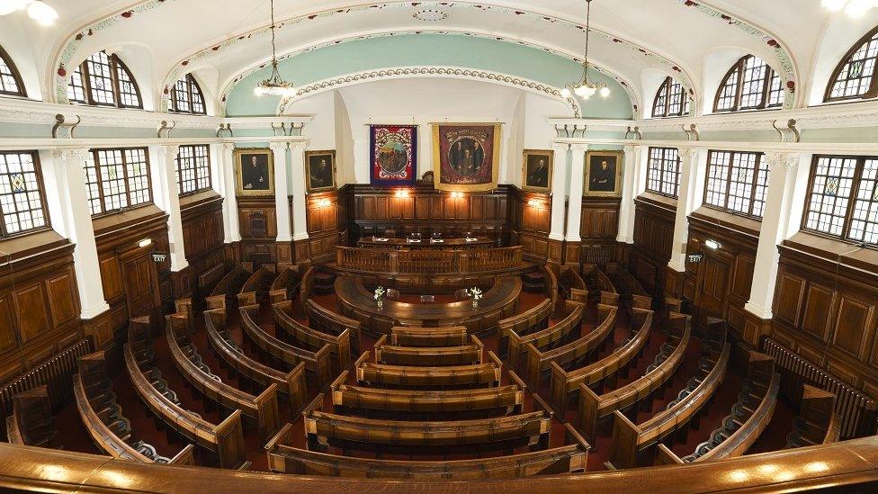 Aerial view of wooden seats arranged in circles looking at a dais in an impressive room