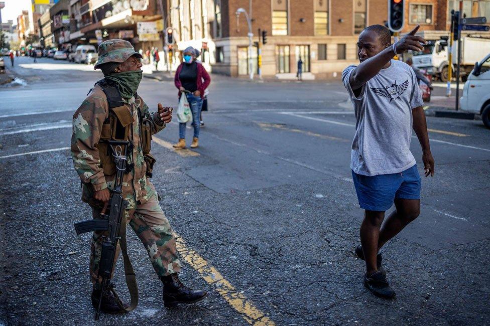 A soldier talks to a man in the street