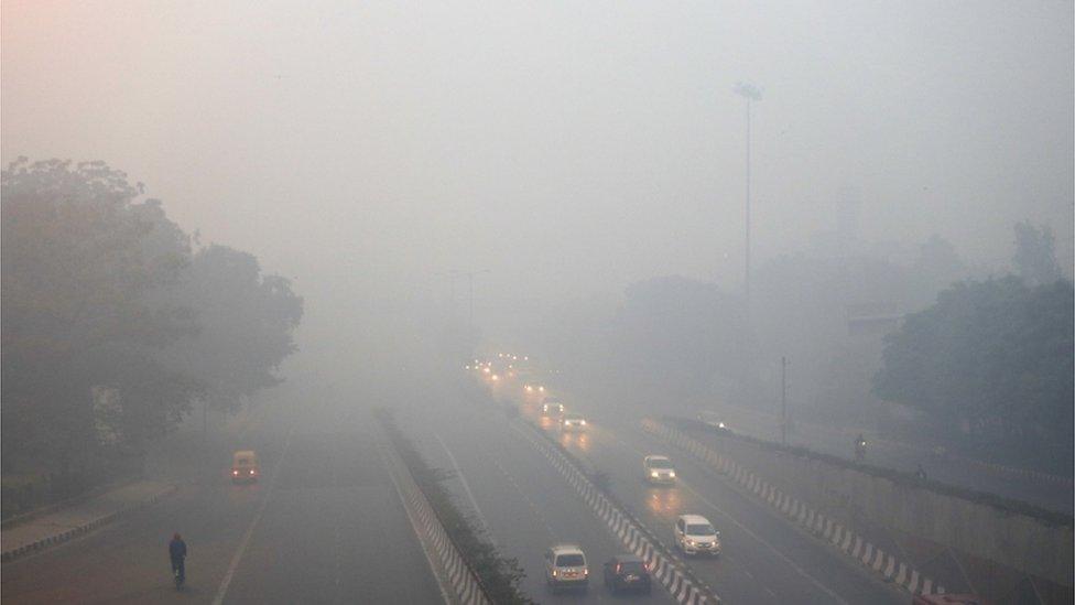 Traffic moves on a road enveloped by smoke and smog, on the morning following Diwali festival in New Delhi, India, Monday, Oct. 31, 2016