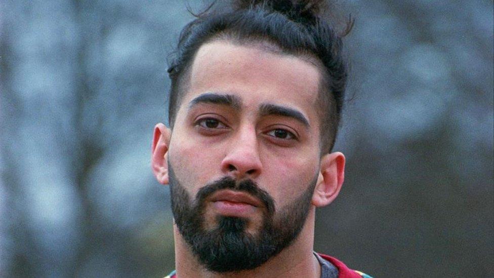 Adil Malik, a bearded Asian man looking at the camera with a slightly tilted head. The background outdoors and is blurred.