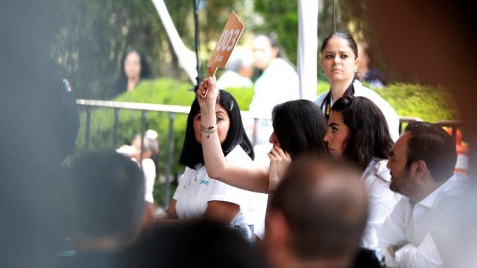 A woman bids during an auction of seized properties from drug traffickers and others, in Mexico City, Mexico on 23 June 2019.