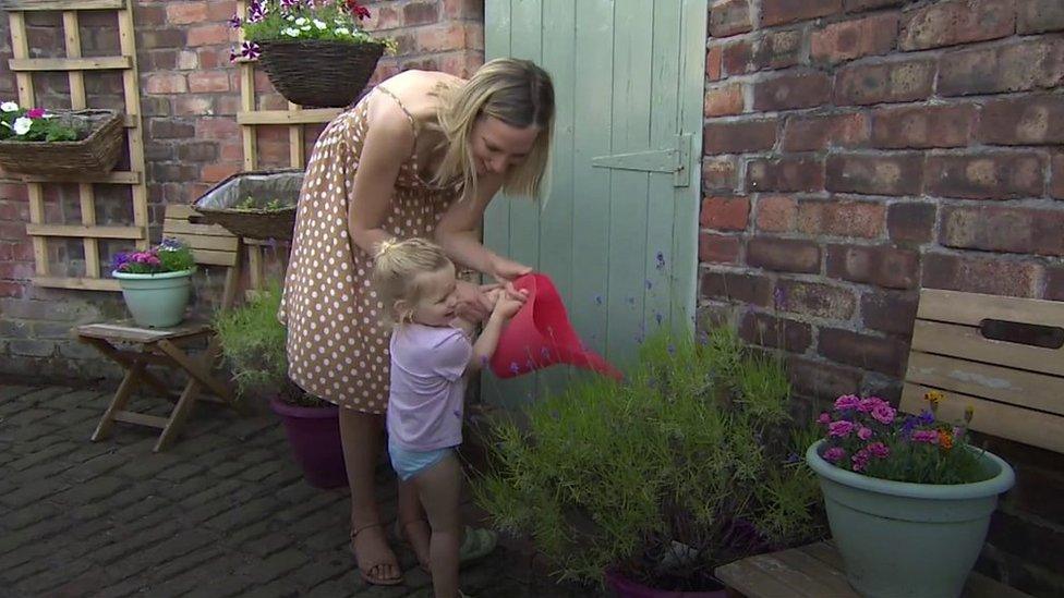 Woman and child water plants in alleyway