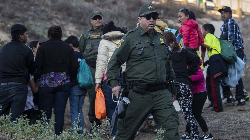 Central American migrants are arrested by US Border Patrol agents after jumping over the metal barrier separating Playas de Tijuana in Mexico from the US, 2 December 2018