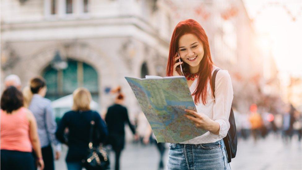 A young woman reading a map in a European city