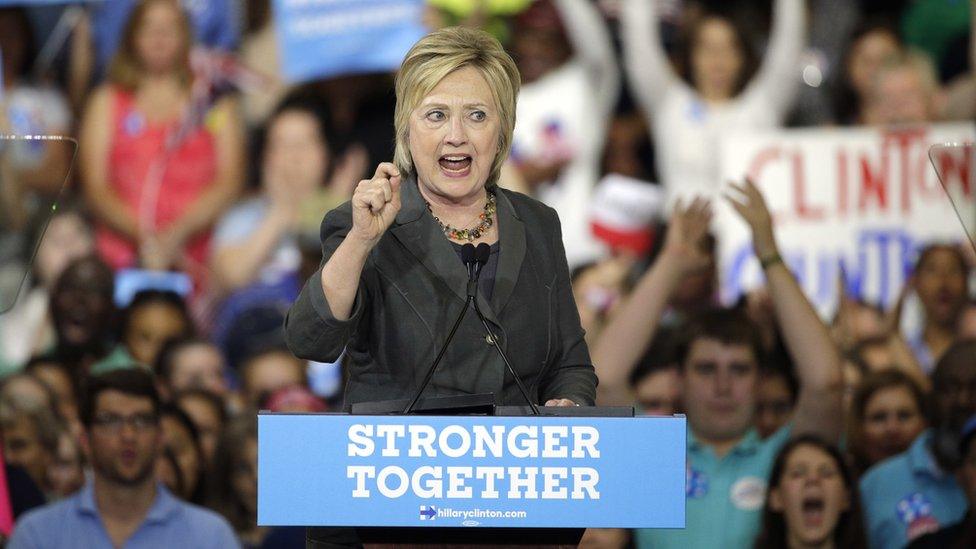 Hillary Clinton at a rally, over a podium labelled "stronger together"