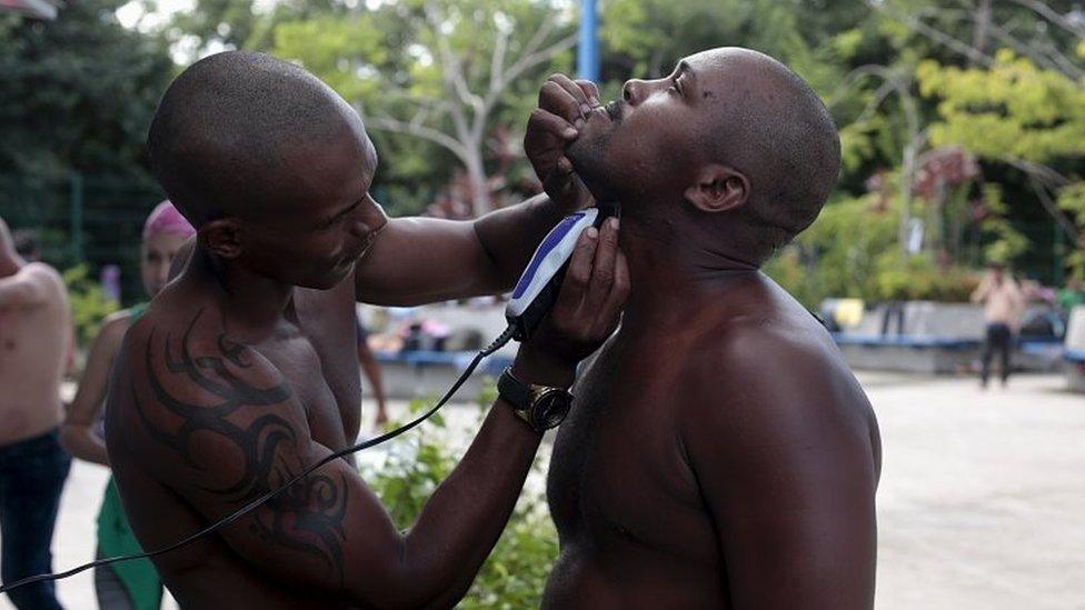 A Cuban migrant trims the beard of a fellow migrant at the border between Costa Rica and Nicaragua in Penas Blancas on 17 November, 2015