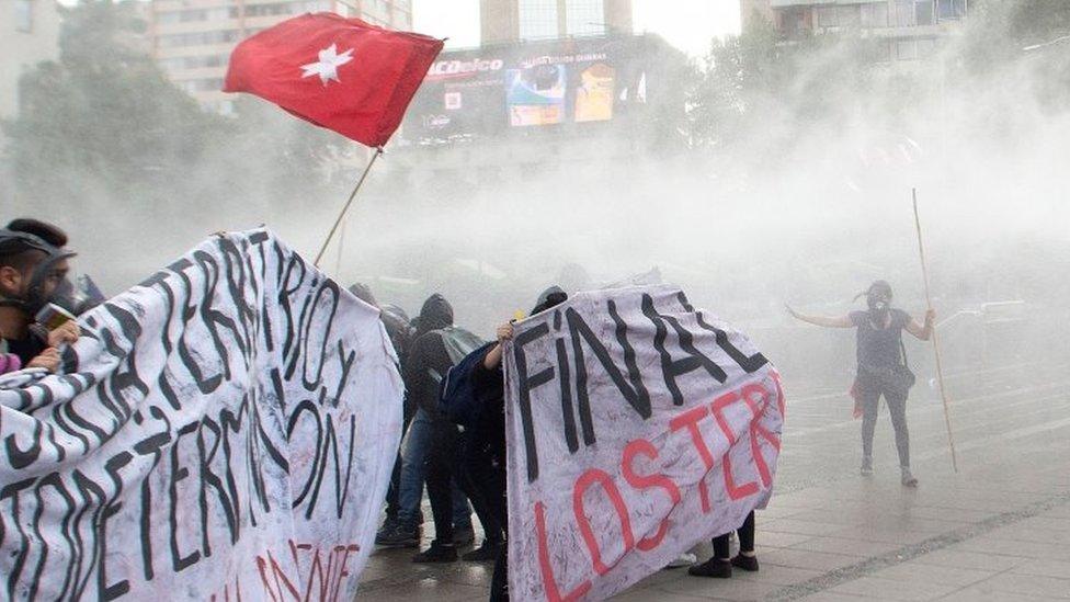 Demonstrators are sprayed by the riot police with water during a protest by Mapuches indigenous people and human rights activists against the government as part of the Mapuches" ongoing fight for the recognition of their rights and demands, as well as for the recent killing by the police of a young Mapuche man, in Santiago, on December 14, 2018. -