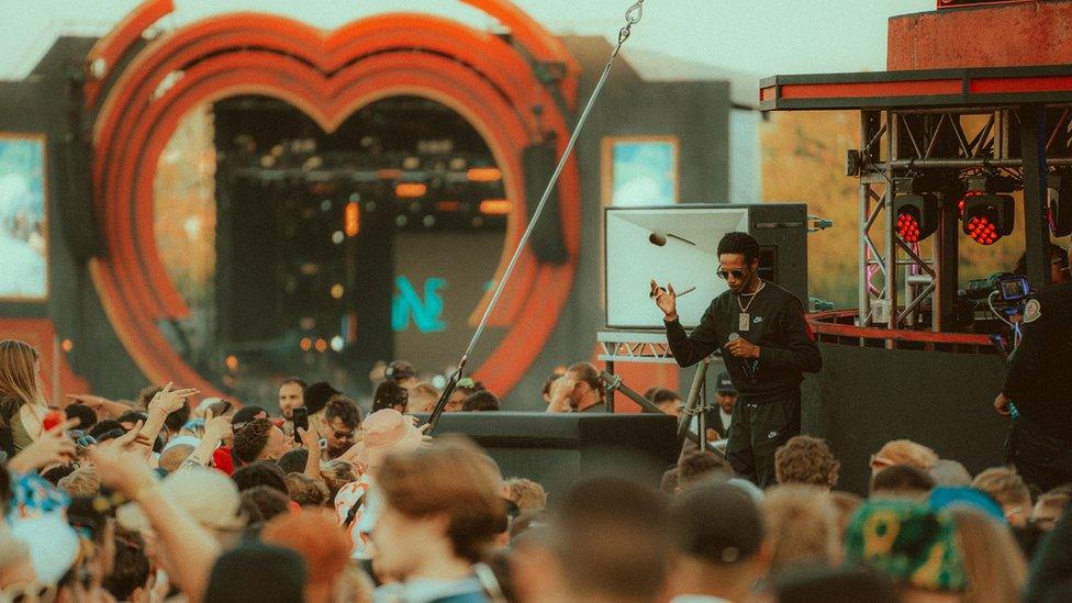 A crowd watching an artist performing at the main stage at Love Saves the Day