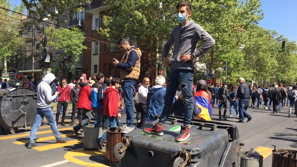 Protesters use rubbish bins to stop the traffic in a road in the capital