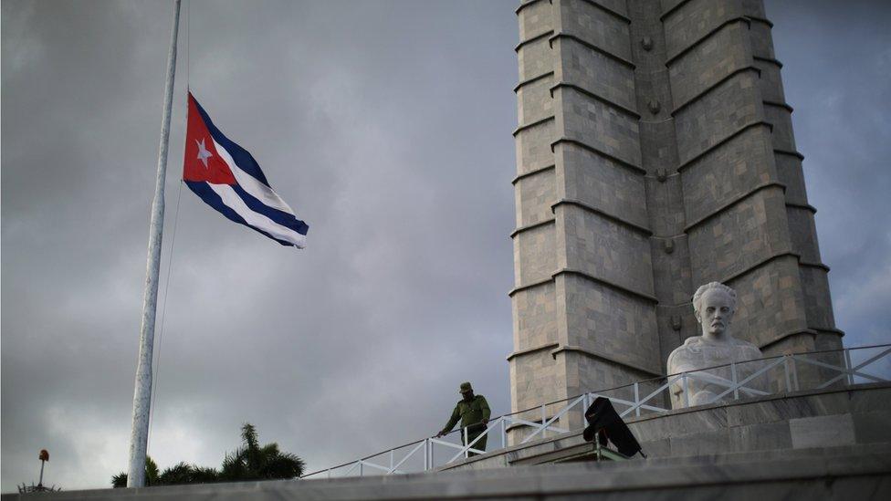 A soldier stands at Revolution Square as a Cuban flag flies at half mast