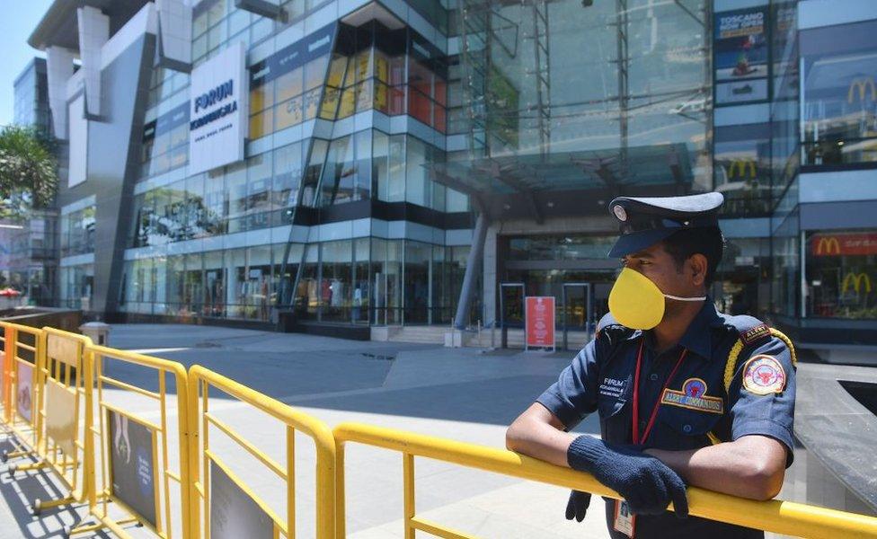 A security personnel stands guard in front of a closed shopping mall amid concerns over the spread of the COVID-19 novel coronavirus, in Bangalore on March 16, 2020.