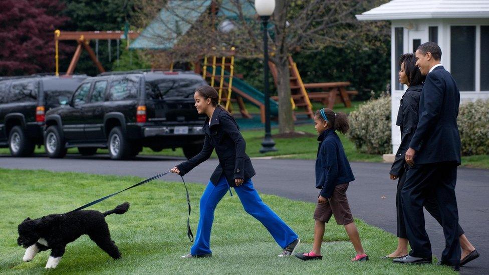 President Obama walks with his wife, daughters and dog