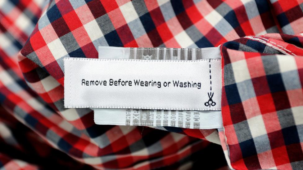 A "Remove before wearing and washing" RFID tag on red checked shirt