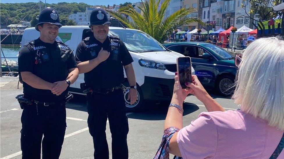 A woman taking a photograph of police officers in Guernsey