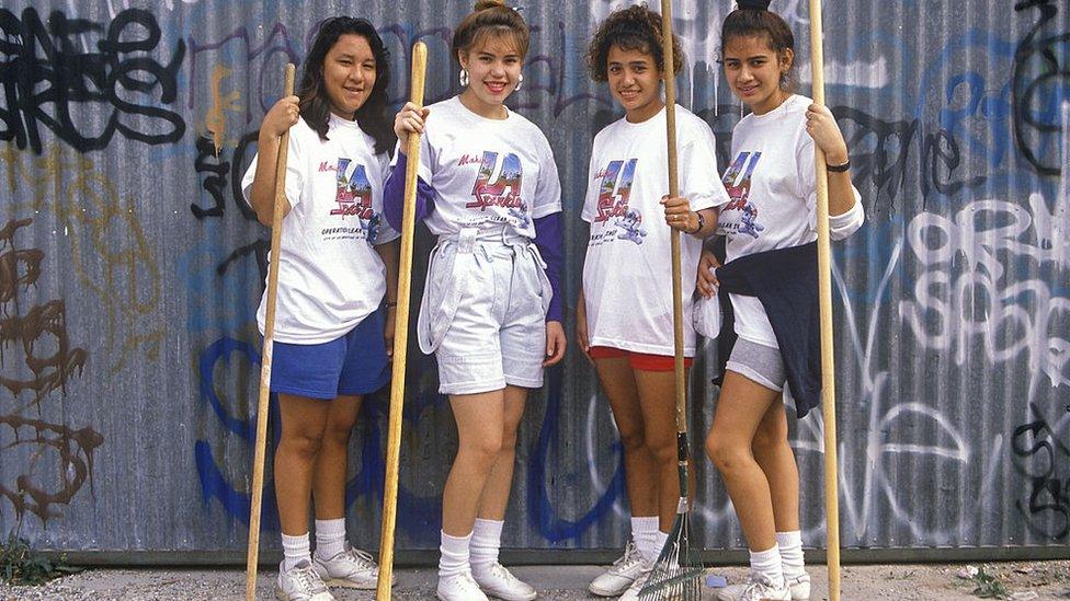 Four girls with brooms and rakes