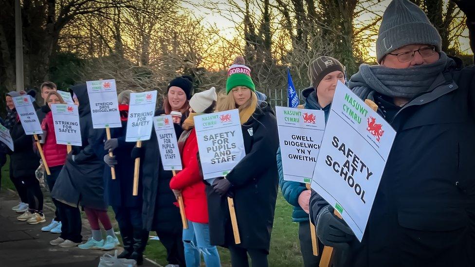 teachers on a picket line holding signs about school safety