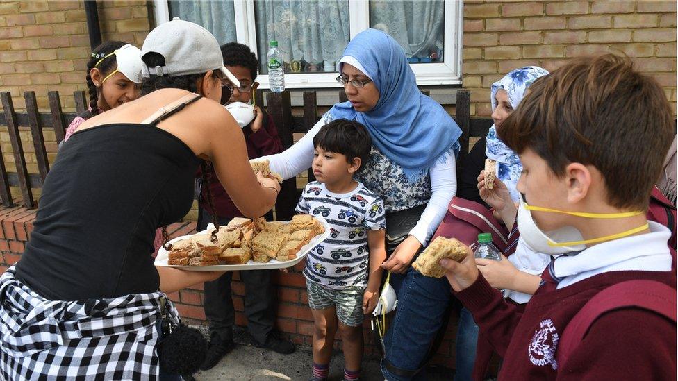 people near fire eat sandwiches