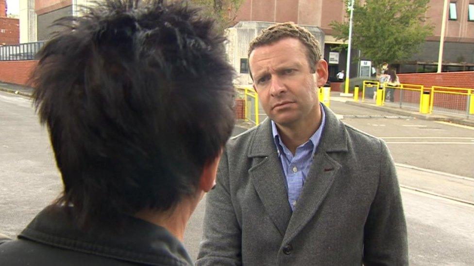 A TV reporter talking to a woman with her back to the camera