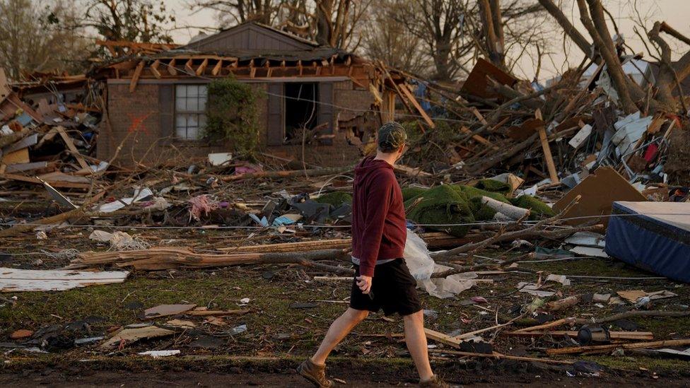 Man walks past his destroyed house