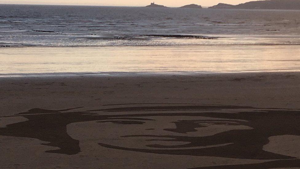 Face painted in the sand while looking out to sea