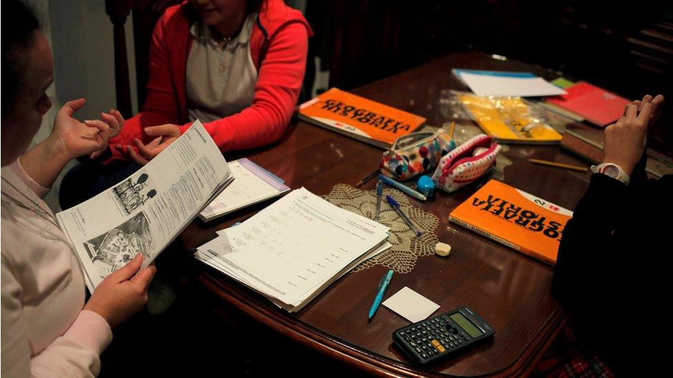 A woman (L) helps to her daughter (R) and a friend to do their homework at their home in Ronda, southern Spain, 2 November 2016.