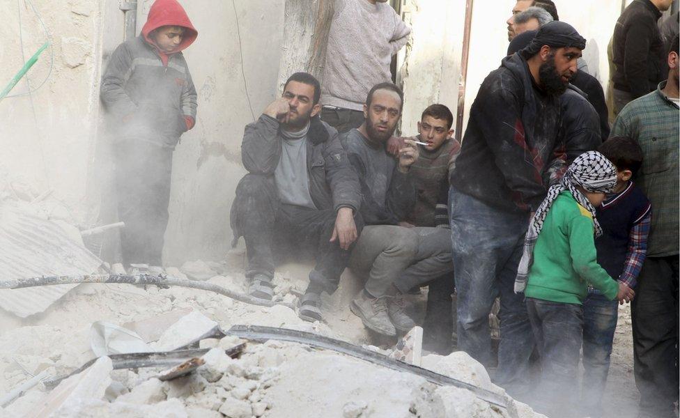 People sit on the rubble of a damaged building in Aleppo after air strikes by the Russian-Syrian government alliance