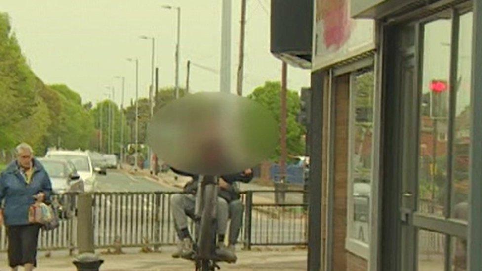 Youths riding moped on pavement