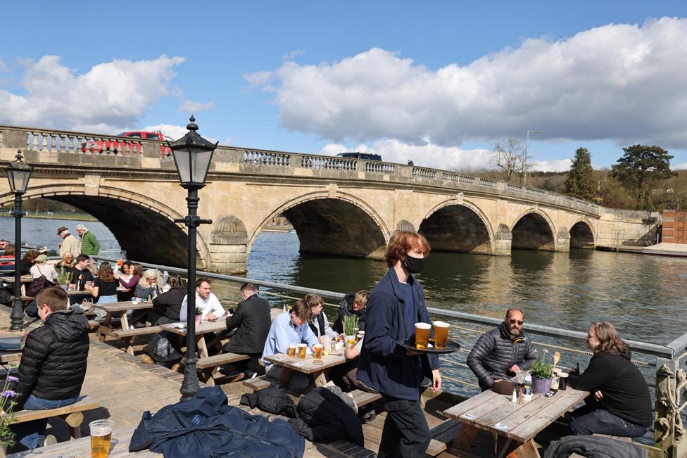 Customers eat and drink on benches next to a bridge