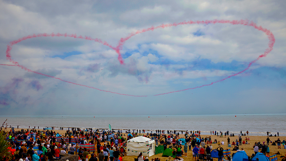 Pink heart in the sky about a crowd on a beach in Swansea