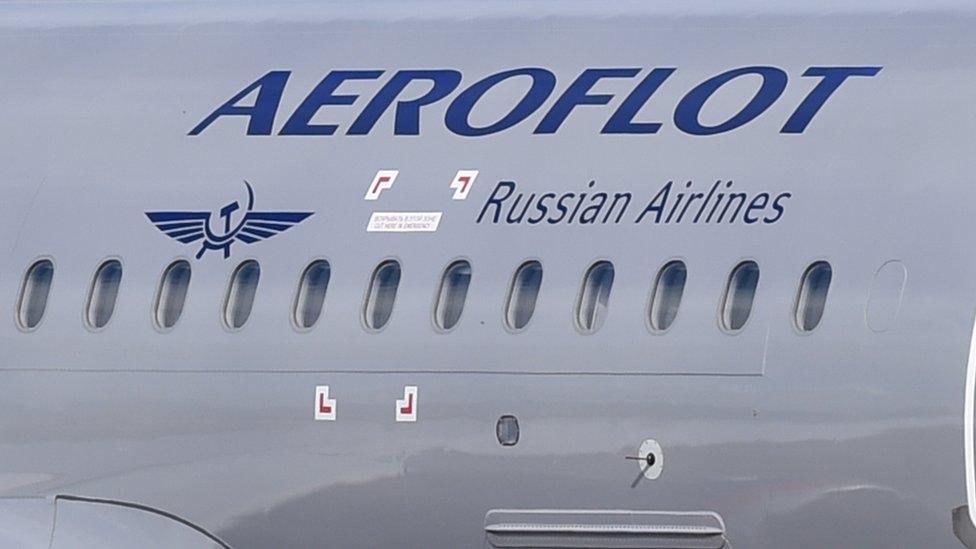 The side of a silver plane with the blue logo of "Aeroflot: Russian airlines" in a decal on the side