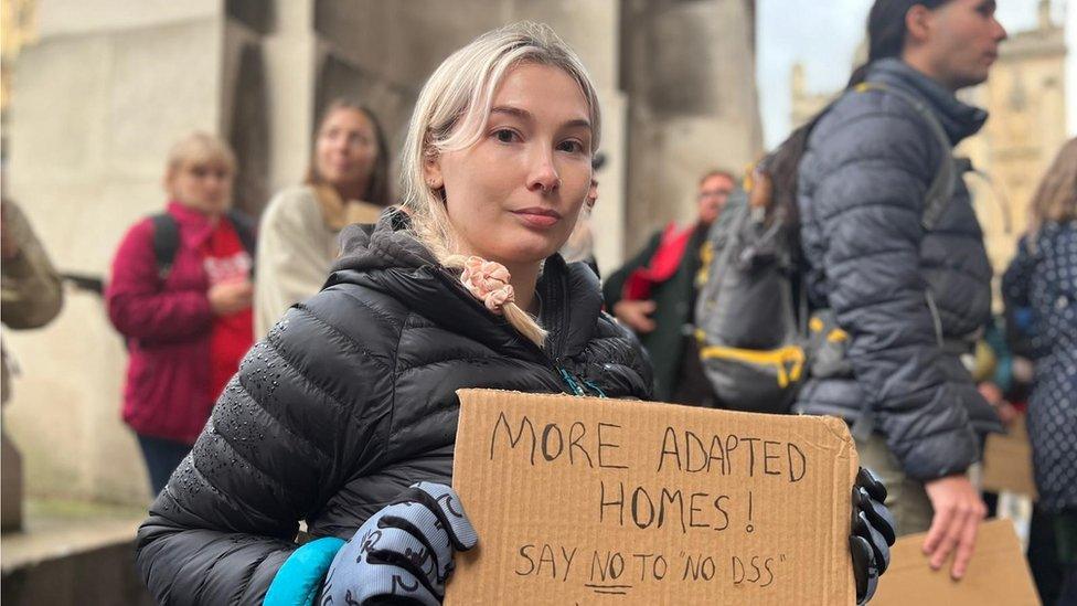 Niamh holding a placard with more adapted homes written on it