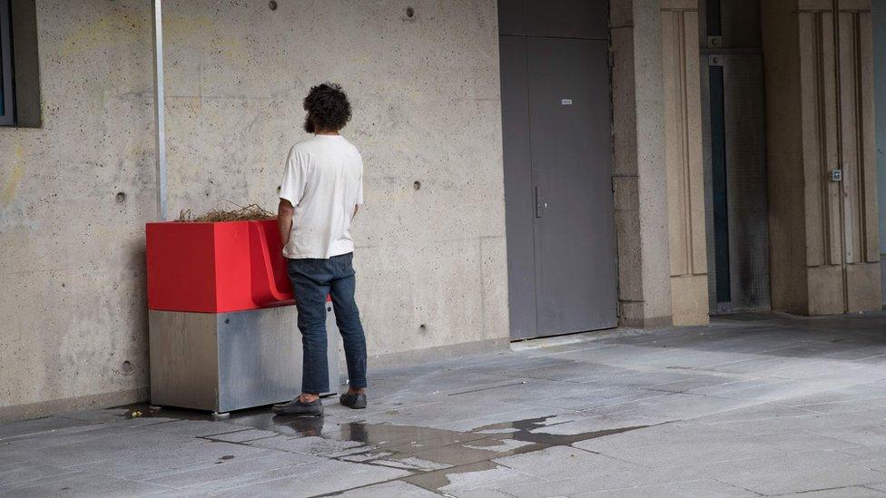 A man uses a "uritrottoir" public urinal on August 13, 2018