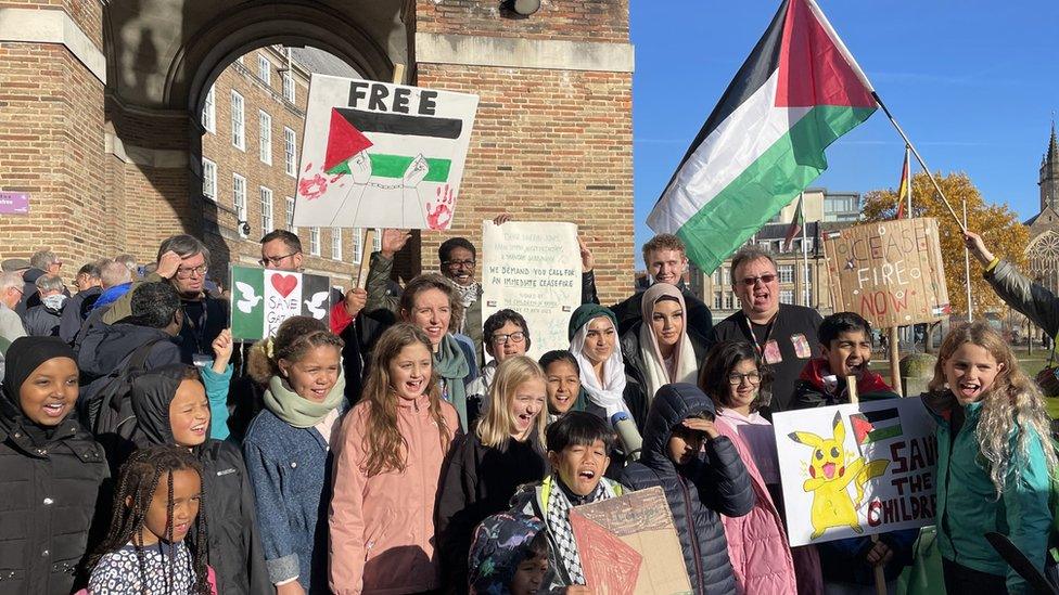 Schoolchildren in Bristol hand in a petition calling for a ceasefire in Gaza to Green Party candidate Carla Denyer (centre, in green scarf), in College Green, Bristol. School Strike for Palestine has been collecting signatures for three weeks on their petition asking the four MPs who represent Bristol to call for a ceasefire in Israel-Palestine.