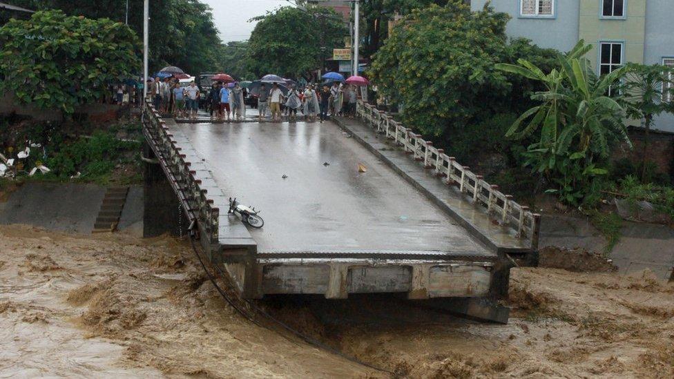 This picture from the Vietnam News Agency taken on 11 October 2017 shows residents standing at an end of a destroyed bridge in the northern province of Yen Bai.