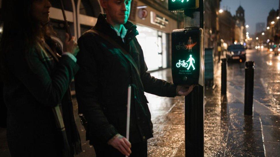 Visually impaired man using a cane at a road crossing