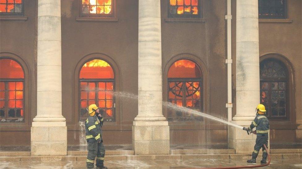 Firefighters battle flames as the library at the University of Cape Town burns after a bushfire broke out on the slopes of Table Mountain in Cape Town, South Africa, April 18, 2021