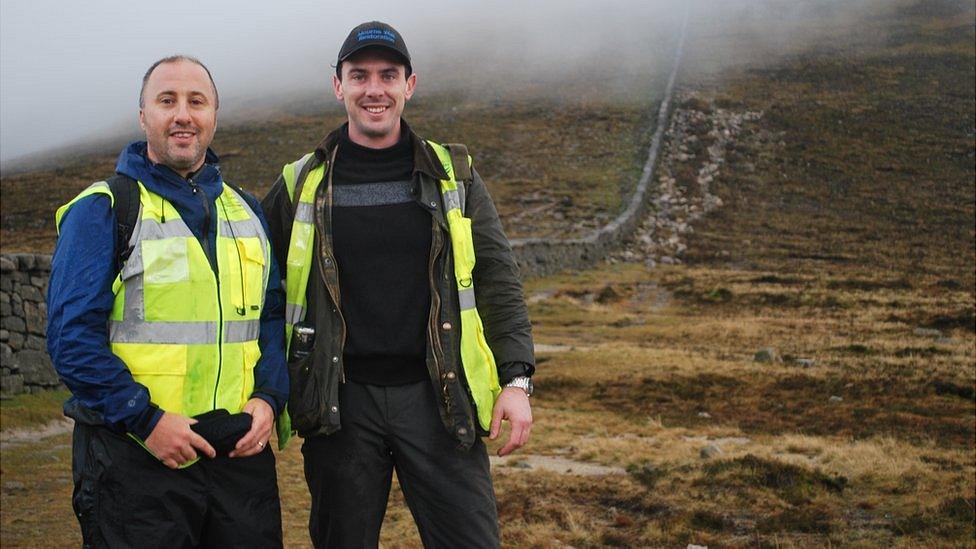 Michal Donnelly and Niall McGovern stand beside the Mourne Wall