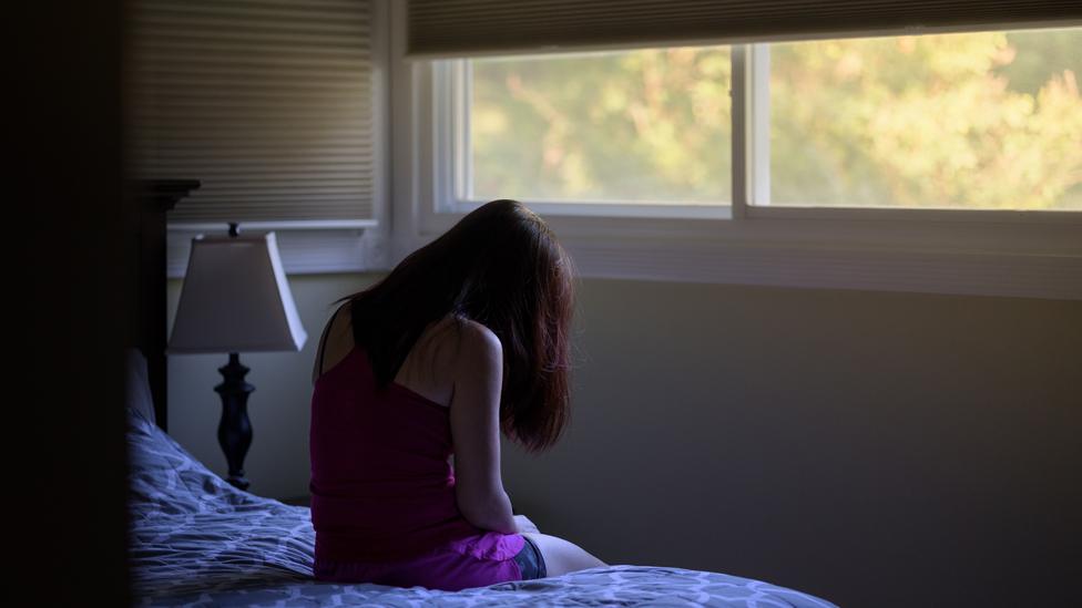 File image of a woman sitting in a room with her head in her hands