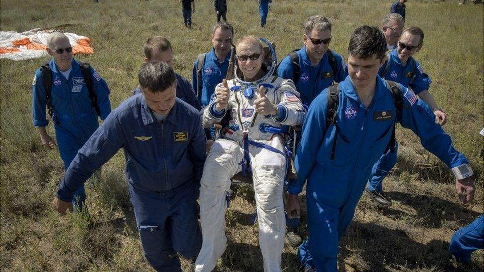 Tim Kopra gives two thumbs up as he is carried to a medical tent after landing back on Earth