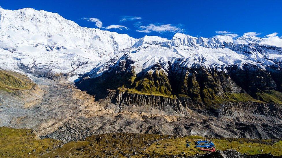 Aerial view on the houses of Annapurna Base Camp, glacier and the snow covered Annapurna 1 North Face in the distance